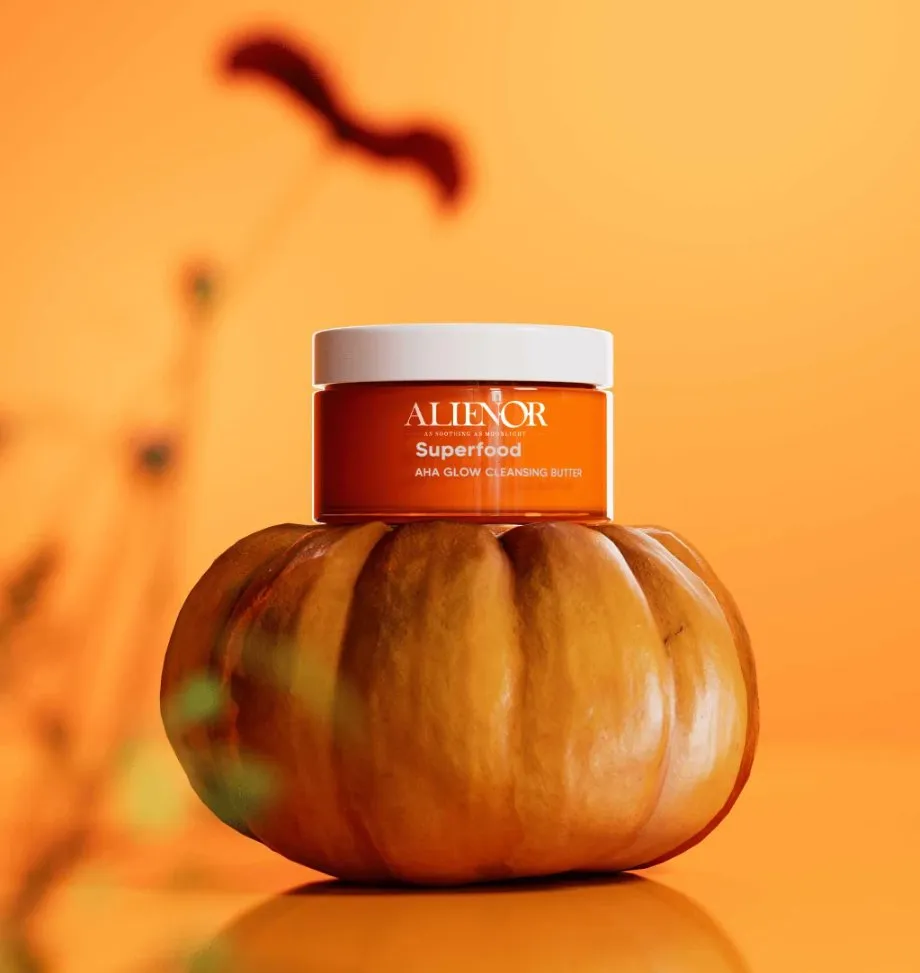 Alienor Superfood AHA Glow Cleansing Butter product photography with vibrant orange packaging on a pumpkin